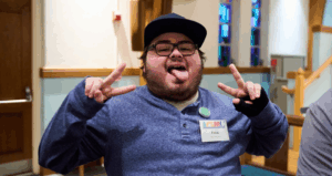 man in a hat holding up two peace signs